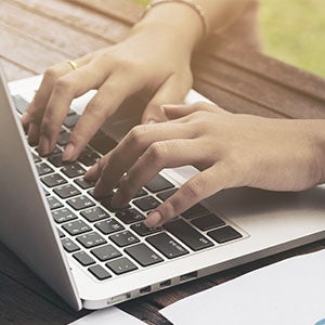 Two hands typing on a laptop